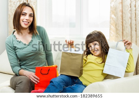 Mother and daughter sitting on sofa at their home with shopping bags,Happiness after shopping