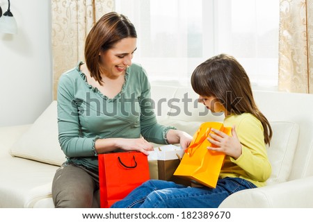 Mother and daughter sitting on sofa at their home and looking what did they bought,Happiness after shopping