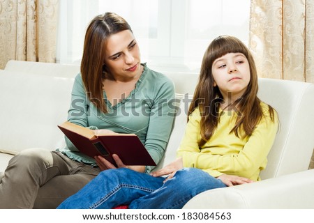 Angry mother is showing her daughter a book,she wants that her daughter read more,but little girl doesn\'t want to,I don`t want to read!