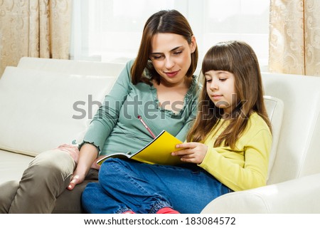 Mother helps daughter with her homework at their home,Help with homework