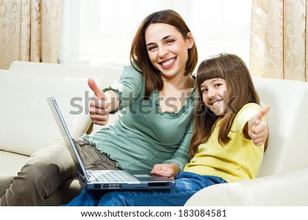 Portrait of mother and daughter showing thumbs up while using laptop together,Mother and daughter using laptop