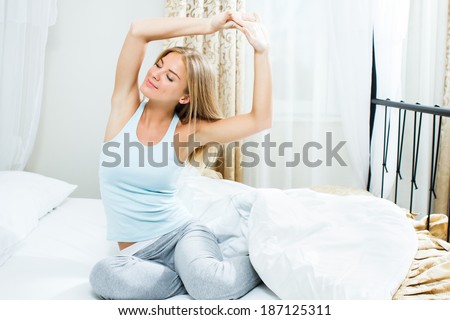 Beautiful blonde woman is stretching in bed,she slept well and is ready for a new day,Beautiful morning
