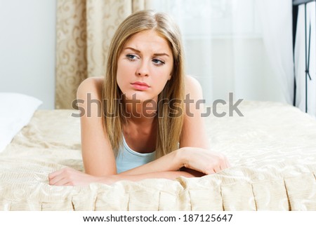 Blonde  woman is lying on  bed in her bedroom and she is very sad because of something,Sad woman