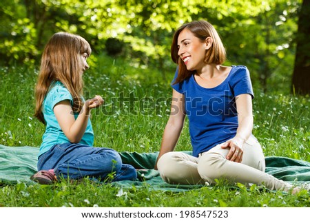 Mother and her daughter sitting in beautiful nature and talking about something,Mother and daughter talking