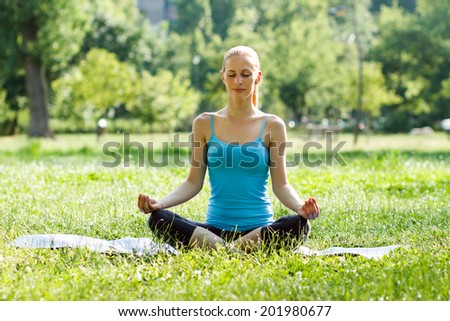 Beautiful woman practicing yoga in the park,Yoga-Ardha Padmasana/Half-lotus pose