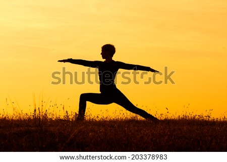 A silhouette of a woman practicing yoga,Yoga-Virabhadrasana /Warrior pose