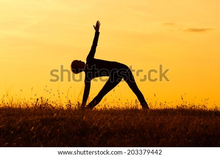 A silhouette of a woman practicing yoga,Trikonasana right/Right triangle pose