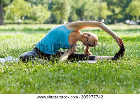 Beautiful blonde woman practicing yoga in the park,Yoga-Parivrtta Janu Sirsasana/Revolved Head-to-Knee Pose