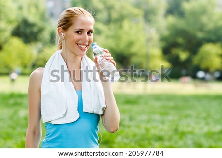Woman is standing in the park and drinking water after exercise,Refreshment after exercise