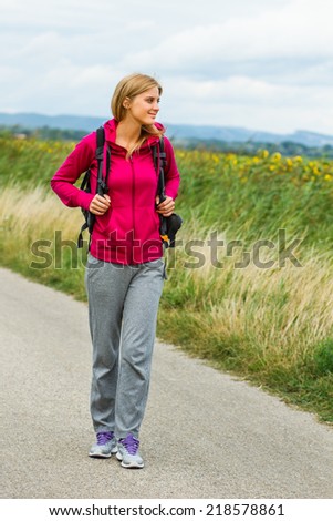 Smiling blonde woman with backpack  enjoys walking the country road,Peace of mind in nature
