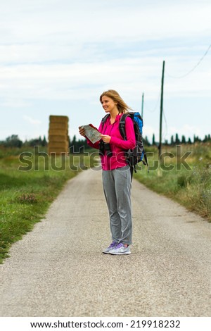 Cheerful blonde woman with backpack  is looking at her map  which way to go,Orientation