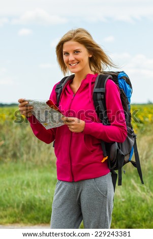 Cheerful blonde woman with backpack is holding a map which will help her to decide which way to go,Orientation