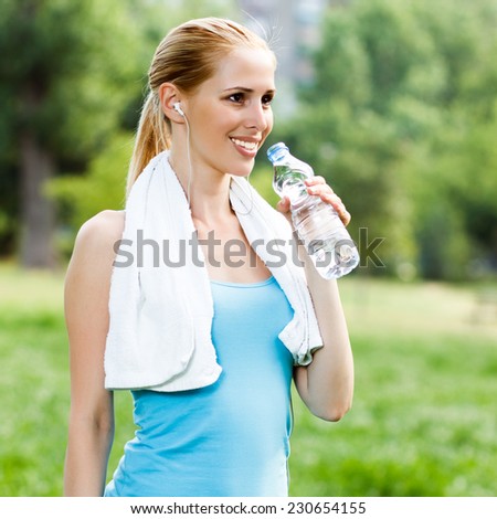 Woman is standing in the park and drinking water after exercise,Refreshment after exercise