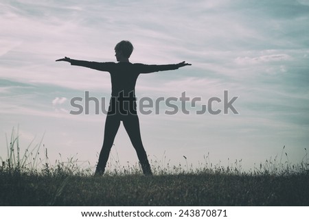 Photo of a woman with her arms outstretched enjoy in nature,intentionally toned image.Peace of mind in nature