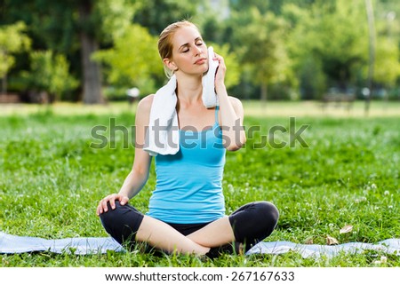 Beautiful blonde woman is cleaning sweat with towel after hard exercise.Woman resting after exercise