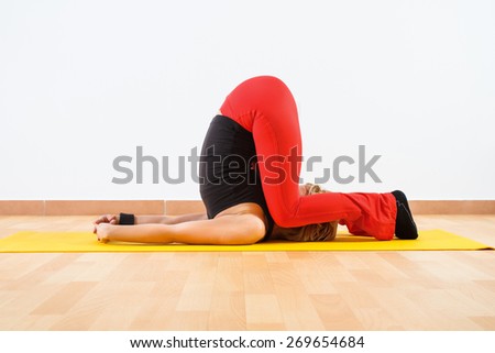 Woman practicing yoga. Yoga-Karnapidasana/Knee To Ear Pose