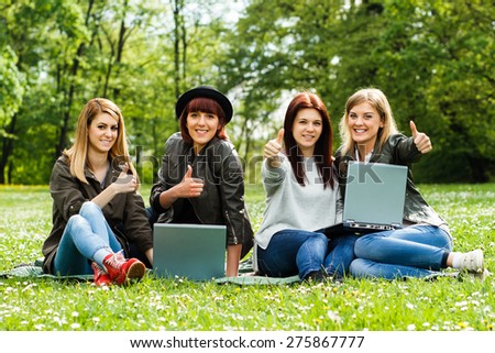 Happy young girls are showing thumbs up while they are using laptop.Thumbs up for technology