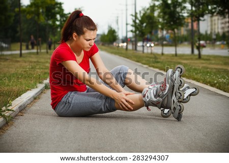 Young girl in roller skates fell down and now she feels pain in her leg.Sport injury