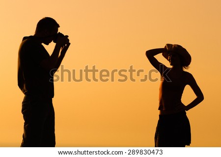 Silhouette of a man photographing woman outdoor.Silhouette of a man photographing woman