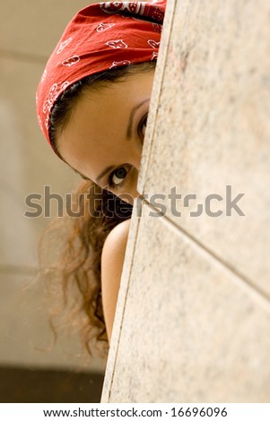 woman in red kerchief looking behind a wall