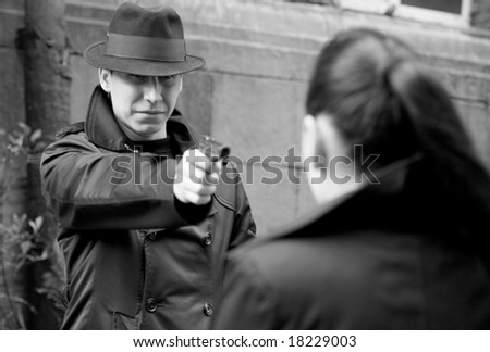 monochrome portrait of man threatens the woman with a pistol