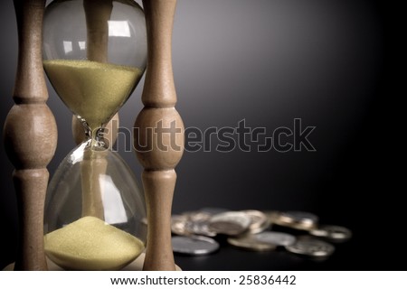 sand clock and coins on black background