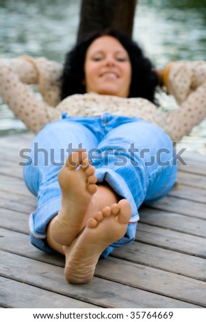 beautiful brunet woman lying near the river. focus on feet.