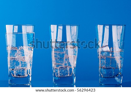 three glasses with cold water on blue background
