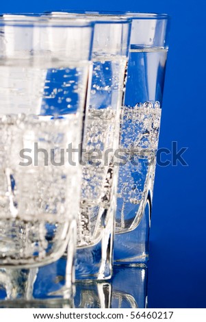 three glasses with cold water closeup on blue background