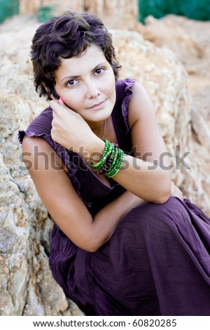 attractive brunet woman in brow dress among rocks in the hot desert