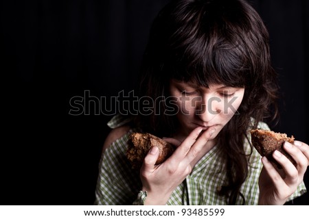 portrait of a poor beggar woman eating bread in her hands