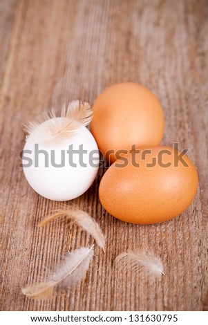 three eggs and feathers on rustic wooden table