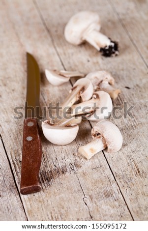 fresh sliced champignons and old knife on old wooden table