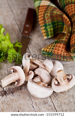 fresh sliced champignons with parsley and old knife on old wooden table