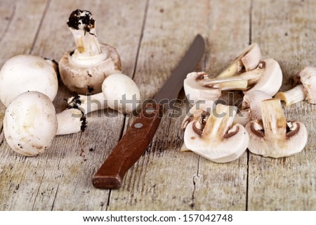 fresh sliced champignons and old knife on old wooden table