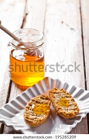 crackers in plate and honey on rustic wooden board