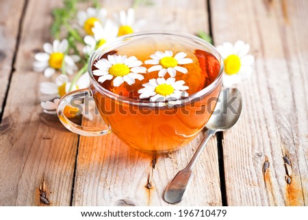 cup of tea with chamomile flowers on rustic wooden background