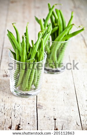 green string beans in glasses on rustic wooden background