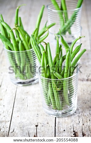 green string beans in glasses on rustic wooden background