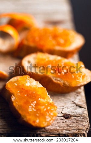 pieces of baguette with orange marmalade closeup on rustic wooden board