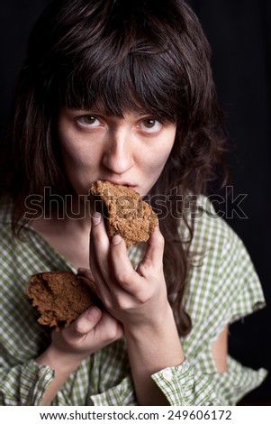 portrait of a poor beggar woman eating bread in her hands