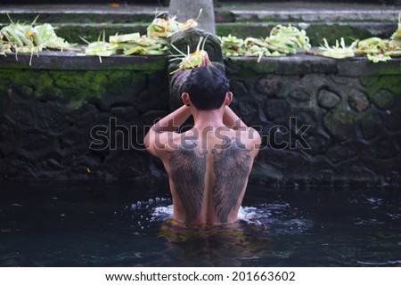BALI, INDONESIA - MAY 30: Worshippers make an offering at the Tirta Empul Temple on May 30, 2014 in Bali, Indonesia. He believe that water from the spring is holy and has the healing power