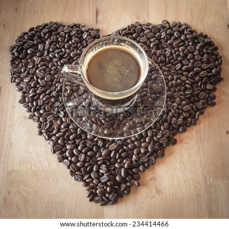 Coffee cup with coffee bean heart on table