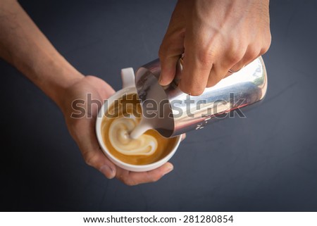 Pouring milk from pitcher to cup of coffee