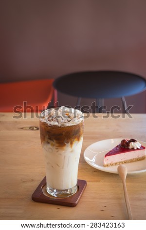 Ice caramel machiato with book and cake on table in coffee shop