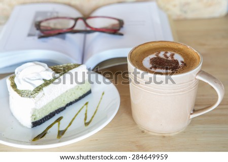 Cup of coffee with cake , book and grass on background