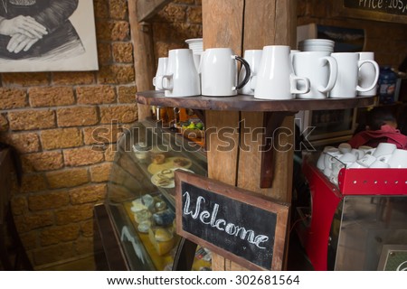 A mug of coffee on wood stand with \' Welcome \' board