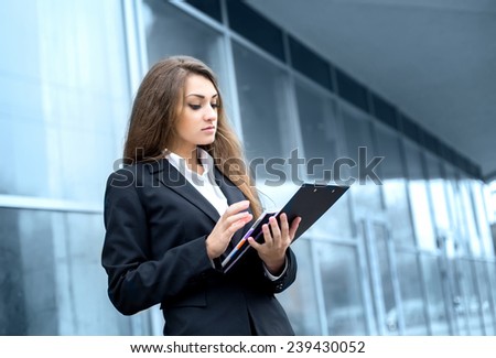 Successful businesswoman or entrepreneur using a digital tablet computer, standing in front of his office.