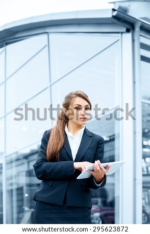Successful businesswoman or entrepreneur using a digital tablet computer, standing in front of his office.