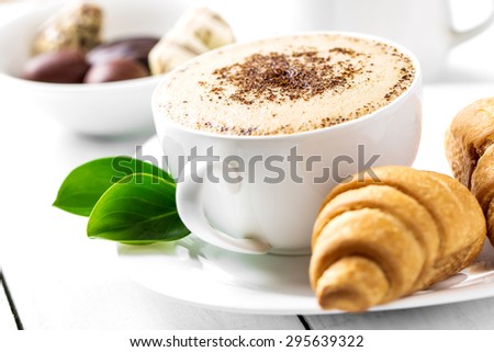 Hot cappuccino and pastries on white wooden boards